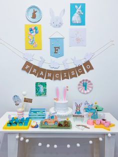 a white table topped with a cake covered in bunting and bunny decorations on top of it