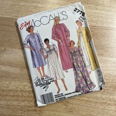 an old sewing book on a wooden table with the cover showing three women's dresses