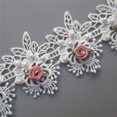 white lace with pink roses and pearls on grey background, close - up shot from above