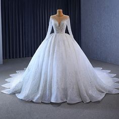 a white wedding dress on display in front of a curtain