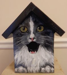 a cat painted on the side of a birdhouse with it's mouth open