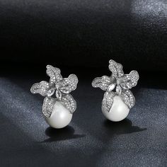 Be the center of attention with these beautiful LILY PEARL EARRINGS. Featuring a delicate LILY design, these earrings are sure to be a perfect addition to any occasion. Pearls delicately embellish the petals- creating a sophisticated and timeless look. Pearl Drop Flower-shaped Bridal Earrings, Elegant Flower-shaped Pearl Earrings For Formal Occasions, Elegant Formal Pearl Earrings With Flower Shape, Elegant Flower-shaped Formal Earrings, Elegant Formal Flower-shaped Pearl Earrings, Elegant Flower Shape Pearl Drop Earrings, Elegant Bridal Earrings With Pearl Drop In Flower Shape, Formal Pearl White Flower Drop Earrings, Elegant Pearl Bridal Earrings In Flower Shape