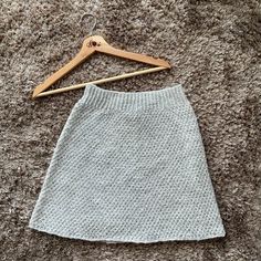 a white skirt hanging on a wooden hanger