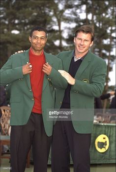 two men standing next to each other in front of a green screen with trees behind them