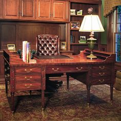 a desk with a lamp and books on it in front of a bookcase filled with books