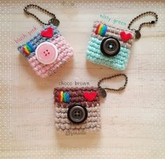 three small crocheted purses with buttons and hearts on them sitting on a table