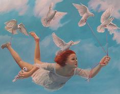 a woman flying through the air while holding two white birds above her head and string