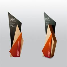 three wooden awards with different colors and shapes on each one, standing side by side in front of a white background