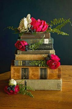 three books stacked on top of each other with flowers in the middle and one sitting on top of them