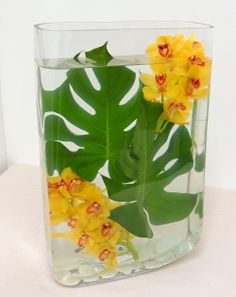 a vase filled with yellow flowers and green leaves