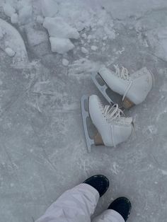 two pairs of white shoes sitting on top of an ice covered ground next to each other