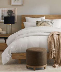 a bed with white comforter and pillows in a bedroom next to a night stand