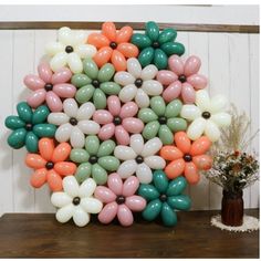 a bunch of balloons in the shape of flowers on a table next to a potted plant