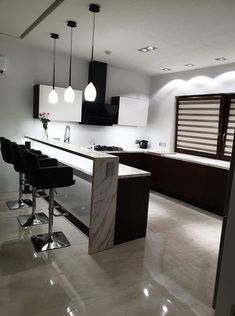 a modern kitchen with marble counter tops and bar stools