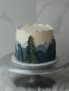 a frosted cake decorated with trees and mountains