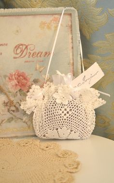 a white doily purse sitting on top of a table next to a box with flowers in it