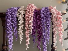 there are many purple and pink flowers hanging from the ceiling