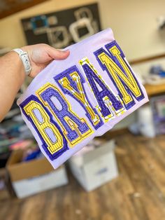 a person holding up a purple and yellow towel with the word rowan written on it