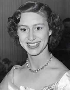 an old photo of a woman wearing a necklace and dress with flowers on the collar