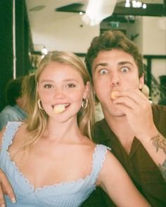 a man and woman are posing for a photo together, one is biting into the other's mouth