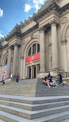 people are sitting on the steps in front of an old building with columns and pillars