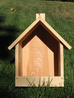 a wooden dog house sitting in the grass