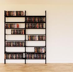 a black book shelf filled with dvd's on top of a hard wood floor