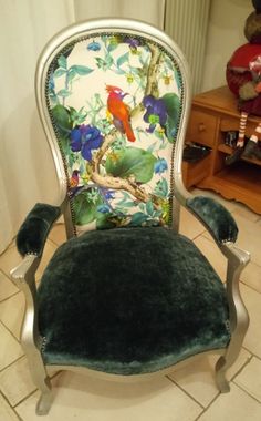 a green velvet chair with a bird on it's back and floral upholstered seat