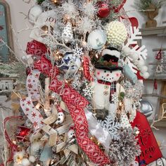 a christmas tree decorated with snowmen and other holiday decorations in red, white and silver