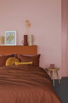 a bedroom with pink walls and brown bedding