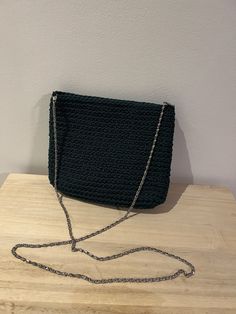 a black purse sitting on top of a wooden table next to a white wall,