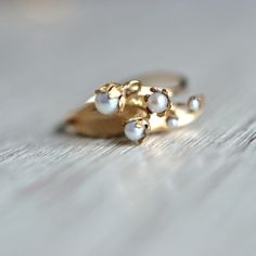 "Gorgeous and Truly Unique Lily of the Valley Ring: Handmade, Nature-Inspired Beauty in 14k Gold - Perfect Gift for June Birthdays\" Embrace the enchanting allure of nature with our stunning Lily of the Valley ring. Meticulously handmade in 14k gold, this exquisite piece showcases exceptional quality and craftsmanship. Its original design captures the delicate essence of the flower, resulting in a truly one-of-a-kind jewelry masterpiece. The centerpiece of this ring features five pearls, each ca Lilly Of The Valley Ring, Lily Engagement Ring, 14k Yellow Gold Pearl Ring With Birthstone, Yellow Gold Pearl Ring With Birthstone In 14k Gold, Heirloom 14k Gold Pearl Ring With Rose Cut Diamonds, Yellow Gold 14k Pearl Ring With Birthstone, Unique 14k Yellow Gold Pearl Ring, 14k Gold Hallmarked Pearl Ring As Gift, Heirloom Pearl Ring Stamped 14k As Gift