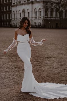 a woman in a white wedding dress standing on the ground with her arms outstretched and hands out