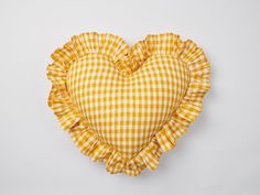 a yellow and white checkered heart shaped pillow on a white background with ruffled edges