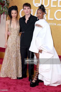 three people posing on the red carpet at an event