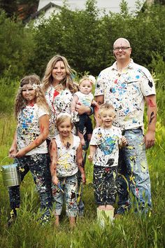 a group of people standing next to each other in the grass with paint all over them