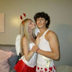 two people dressed in costumes standing next to each other and one is kissing the other