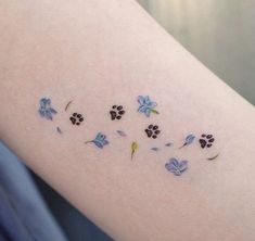 a woman's arm with small blue flowers and paw prints on the back of it