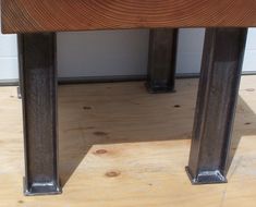 a close up of a wooden bench with metal posts on the bottom and wood top