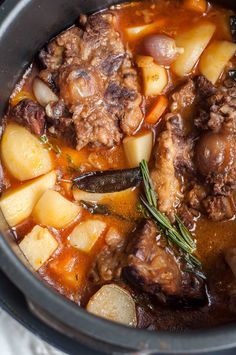 a pot filled with stew and potatoes on top of a table