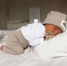 a baby wearing a hat and sleeping on a bed