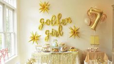 a table with gold decorations and balloons in the shape of stars is set up for a party