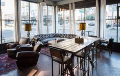 a living room filled with lots of furniture and large windows overlooking the city street in front of it