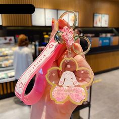 a person holding up a pink keychain with a cartoon character on the front