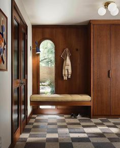 a wooden bench sitting in the middle of a room with checkered flooring and cabinets