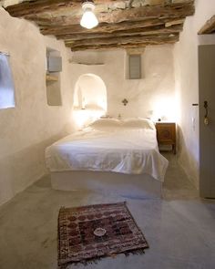 a bed sitting in a bedroom next to a rug on top of a white floor