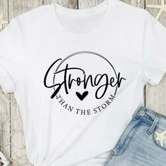 Empower yourself or a loved one with our 'Stronger than the Storm' Inspirational Script T-Shirt, a symbol of strength and determination during life's challenges. This stylish tee features the uplifting quote "Stronger than the Storm" elegantly rendered in a beautiful script font, accompanied by a heart motif. It's the perfect gift for those facing adversity or anyone in need of a reminder that they can overcome any storm that life presents. T Shirt Quotes Women, Images For T Shirt Printing, Motivational T Shirts Quotes, Fun Shirts Sayings, Inspirational Shirts Women, Inspirational T Shirts For Women, Quotes For T Shirts Design, Inspirational Shirt Ideas, Inspirational Tshirts Ideas