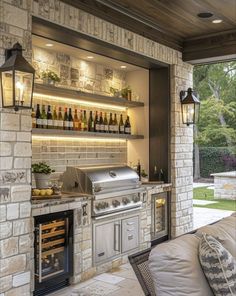 an outdoor kitchen with stone walls and built - in bbq grill, seating area