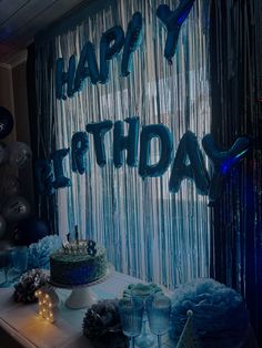 a birthday cake and cupcakes on a table in front of a curtain with the words happy birthday