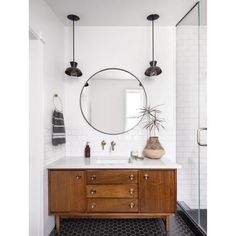 a bathroom vanity with a round mirror above it